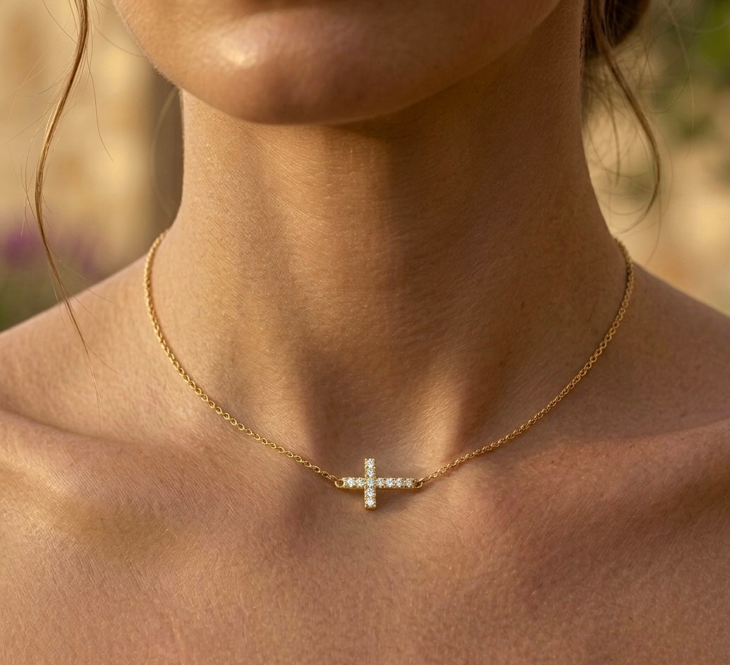 Gros plan sur le décolleté d'une femme portant un collier ras-de-cou en or jaune 18 carats avec une croix horizontale sertie de diamants naturels.