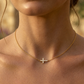 Gros plan sur le décolleté d'une femme portant un collier ras-de-cou en or jaune 18 carats avec une croix horizontale sertie de diamants naturels.