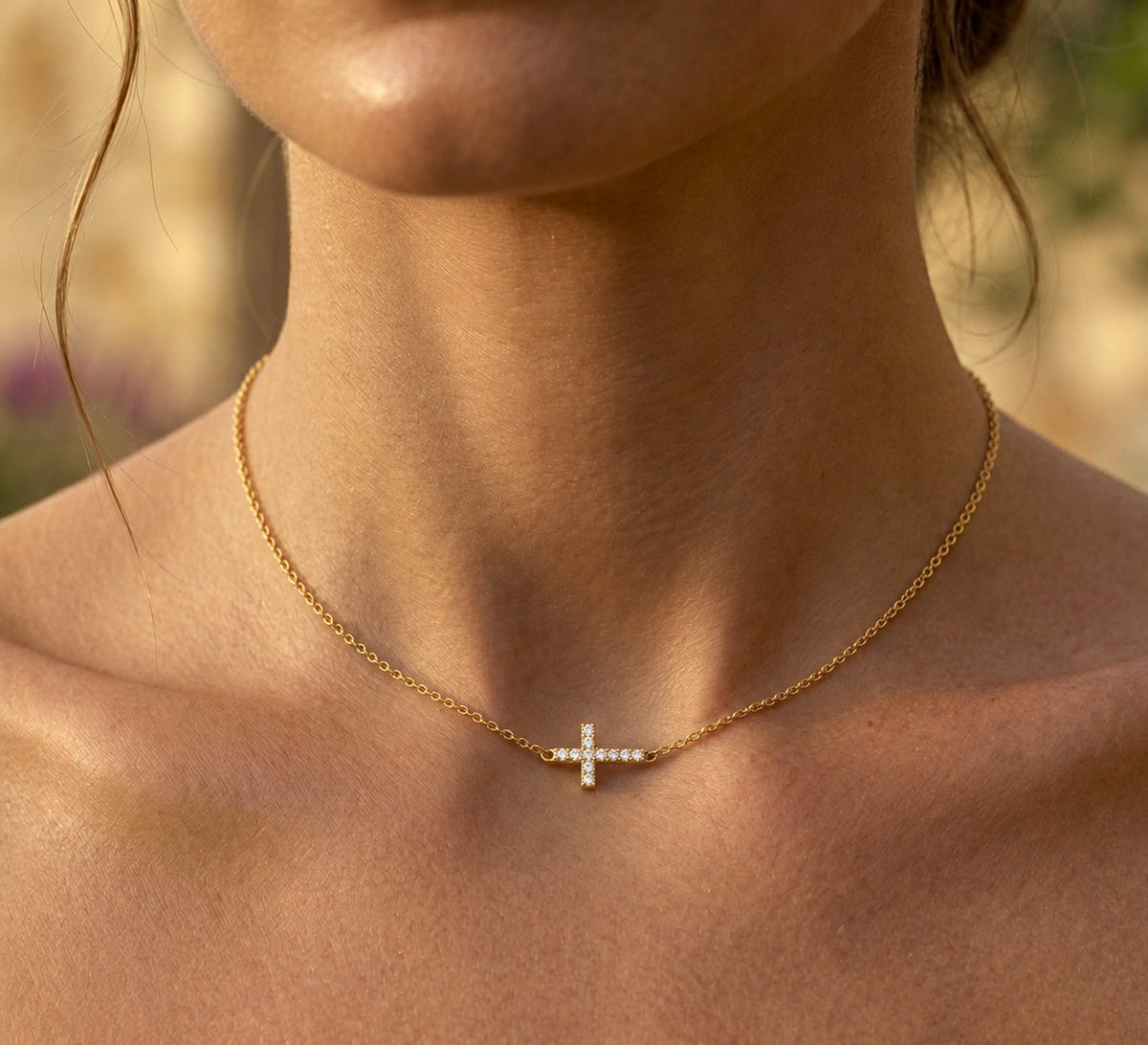 Gros plan sur le décolleté d'une femme portant un collier ras-de-cou en or jaune 18 carats avec une croix horizontale sertie de diamants naturels.