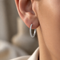 Créole diamants en or blanc 18 carats (or gris naturel) portée délicatement au lobe d'une femme.