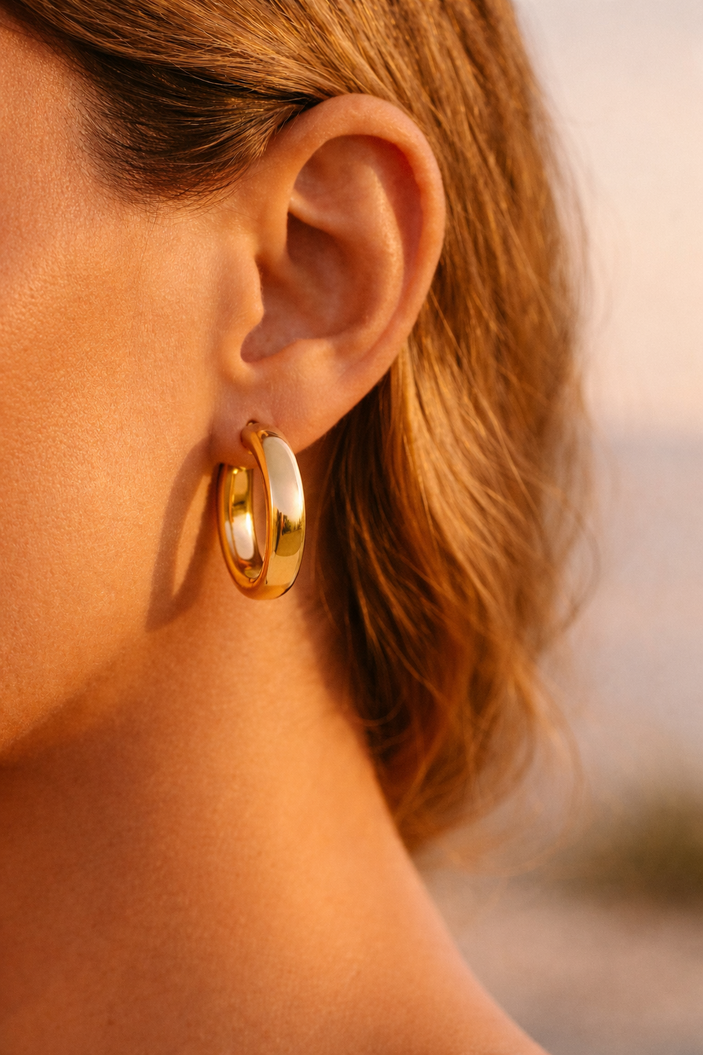 Femme portant des boucles d'oreilles créoles or jaune 18 carats épaisses et larges diamètre 20mm