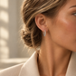 Boucles d'oreilles créoles or blanc et diamants 18 carats portées par une jeune femme en blazer élégant.