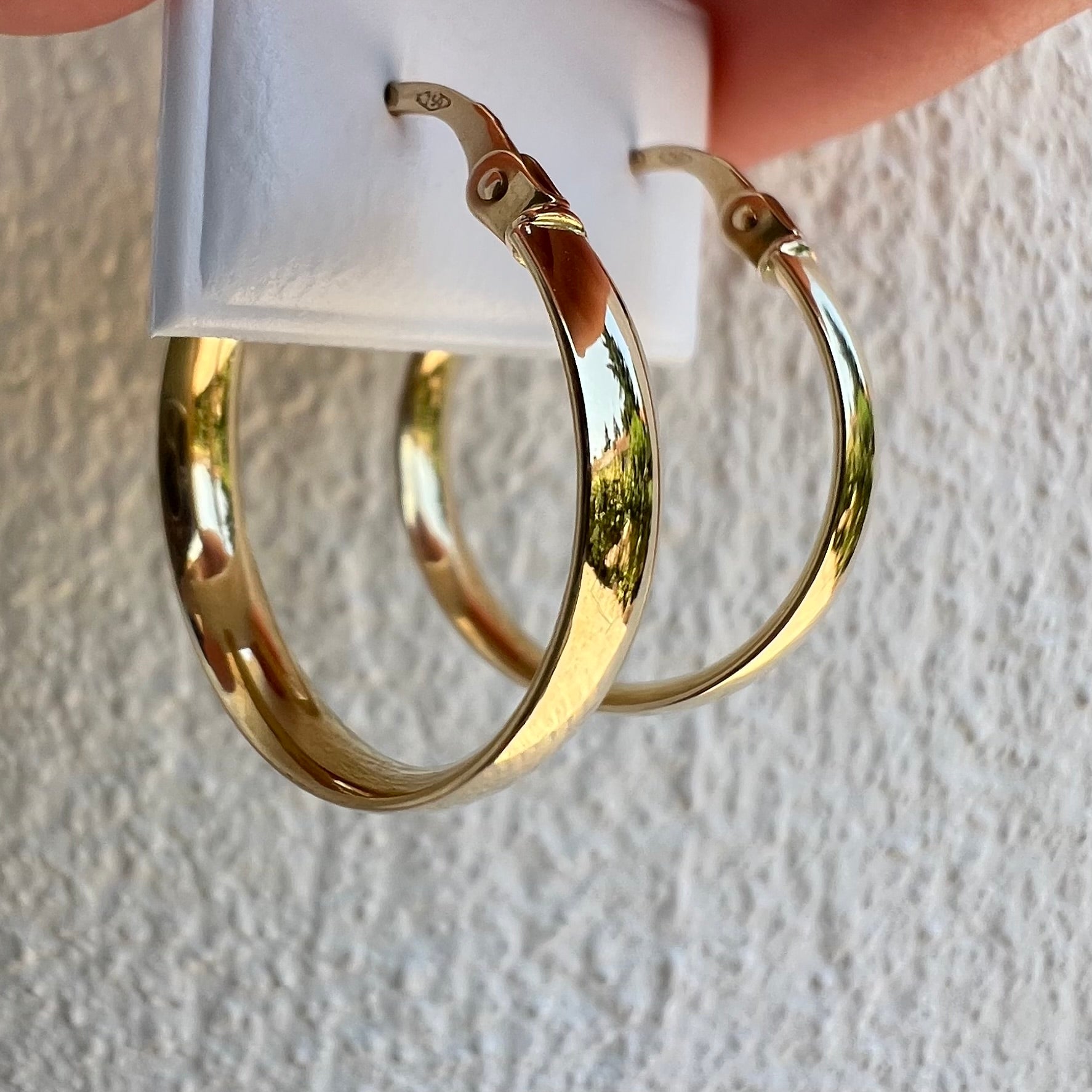 Créoles épaisses en or jaune 18 carats révélant un éclat poli miroir sous la lumière naturelle.