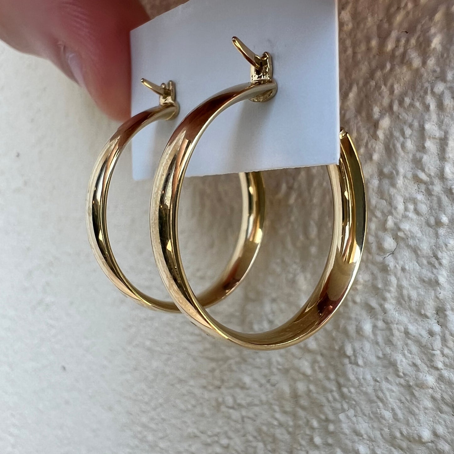 Détail technique de l'arrière et de la charnière pivotante des boucles d'oreilles créoles épaisses en or jaune 18 carats.