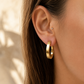 Créole ovale en or jaune 18 carats portée au lobe d'une femme.