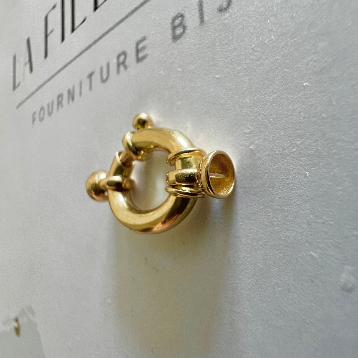 Détail des embouts cloches d'un fermoir bouée ovale en or jaune massif, prêt à être monté sur un collier de perles
