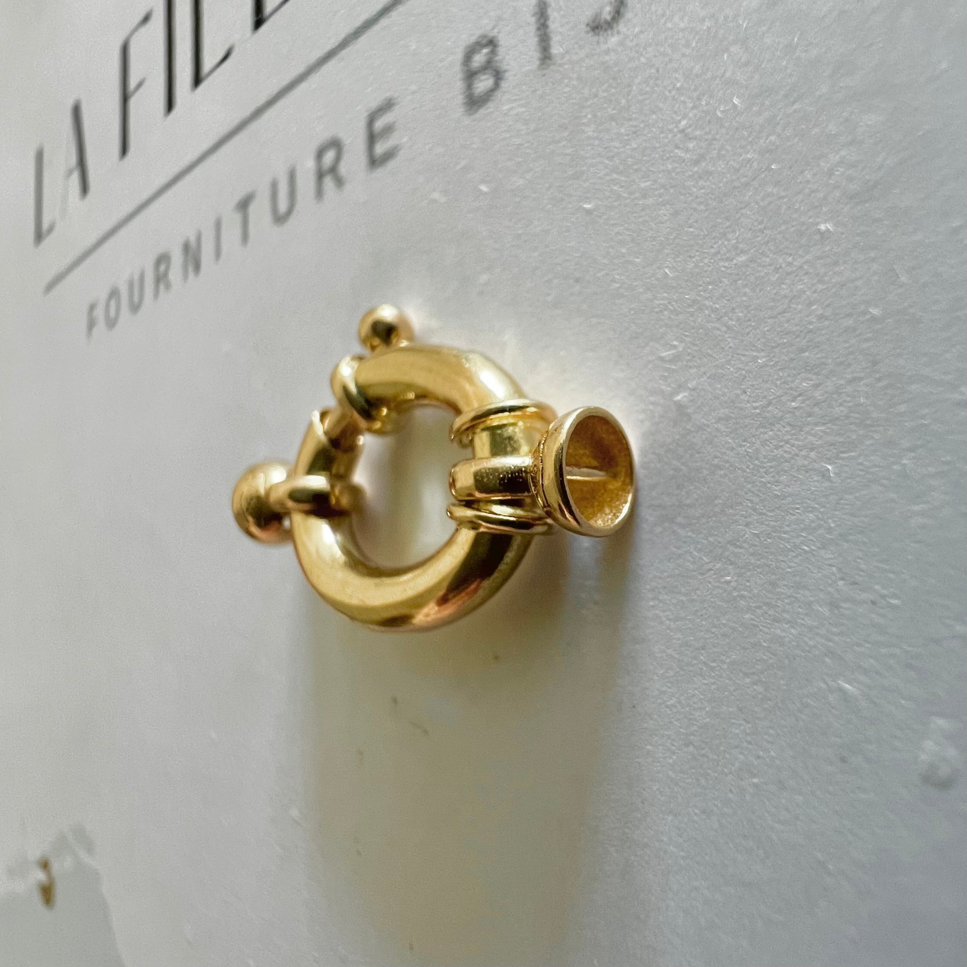Détail des embouts cloches d'un fermoir bouée ovale en or jaune massif, prêt à être monté sur un collier de perles
