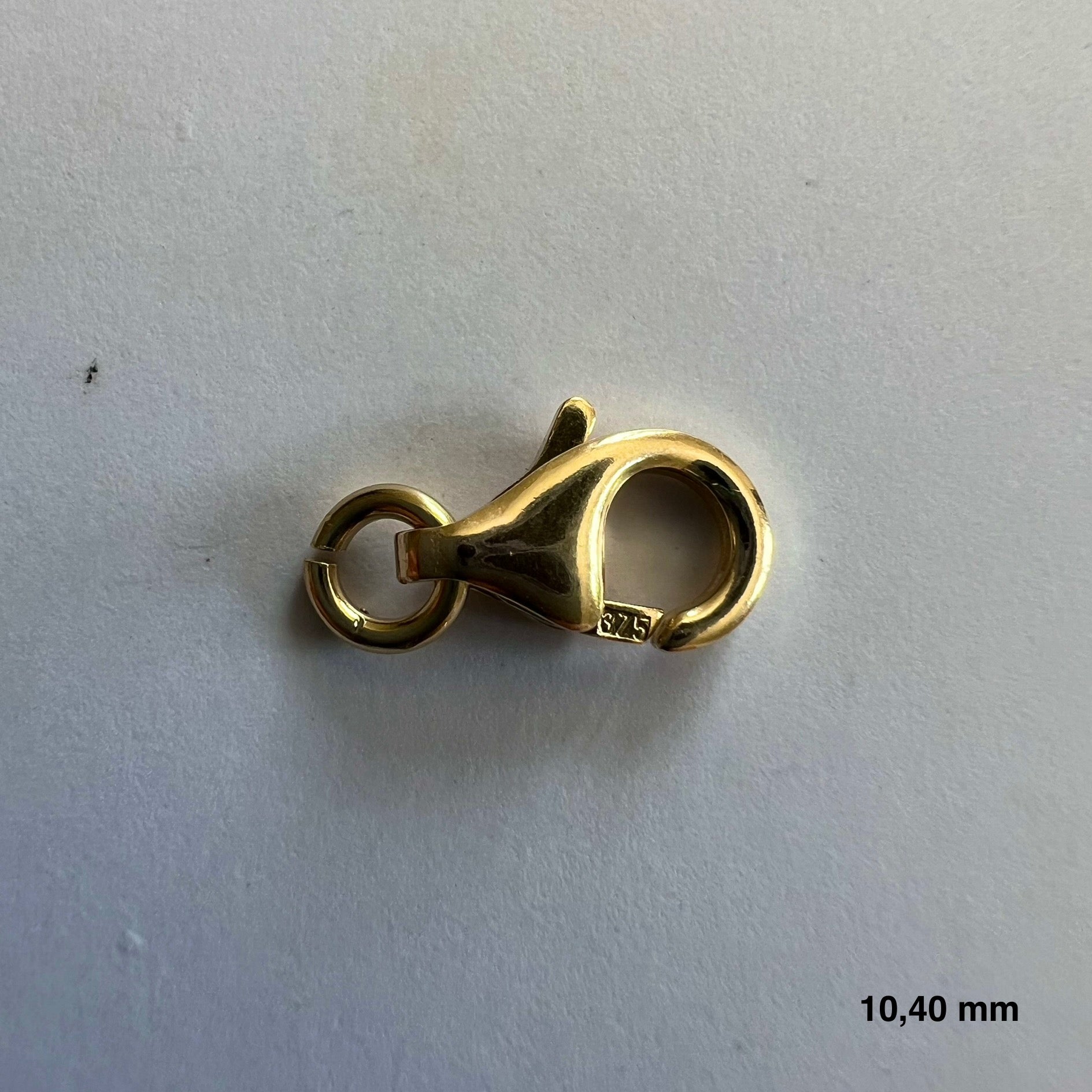 Détail de la finition bombée et polie d'un fermoir mousqueton en or 375 millièmes.