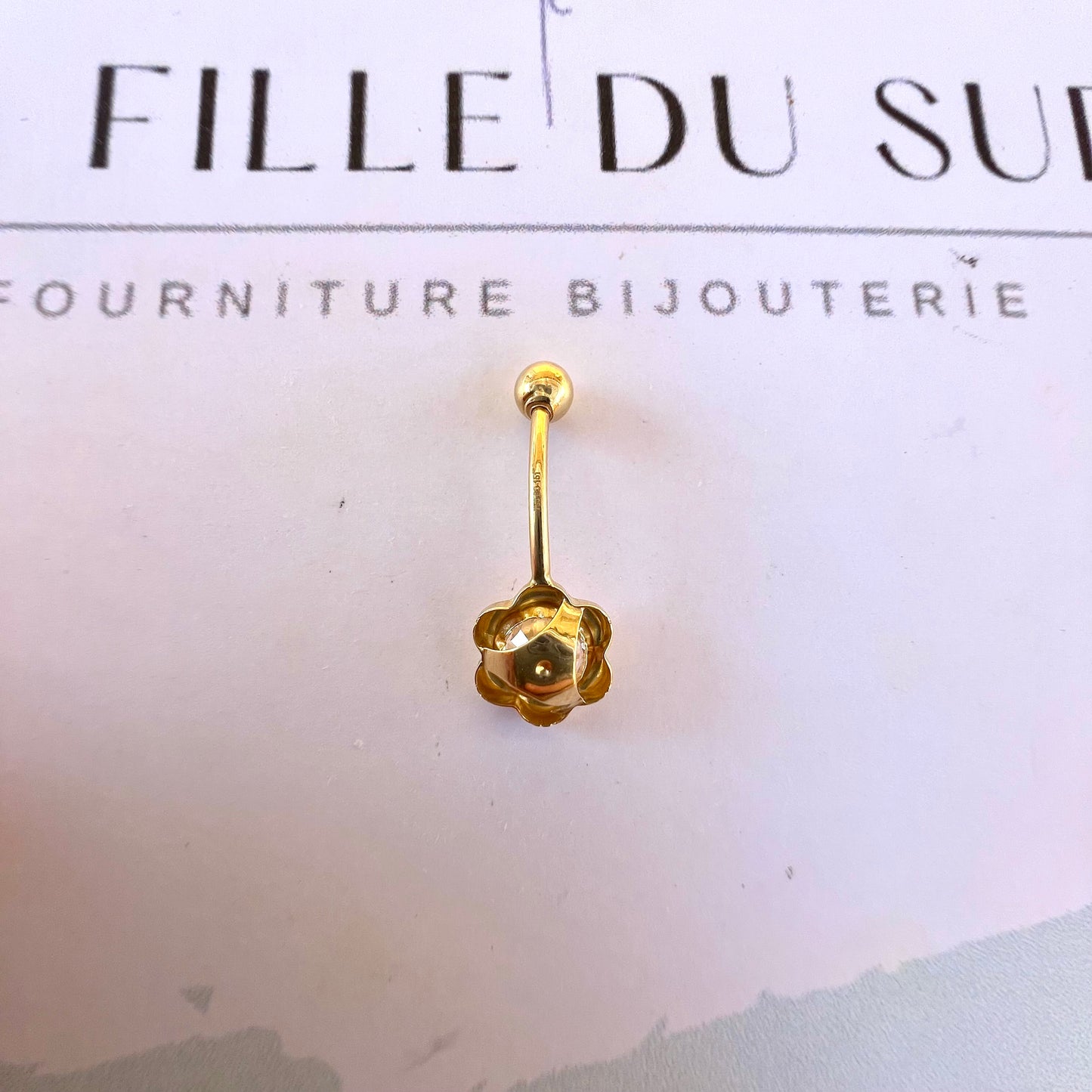Vue arrière du motif fleur du piercing de nombril en or jaune, montrant les finitions soignées de l'atelier.