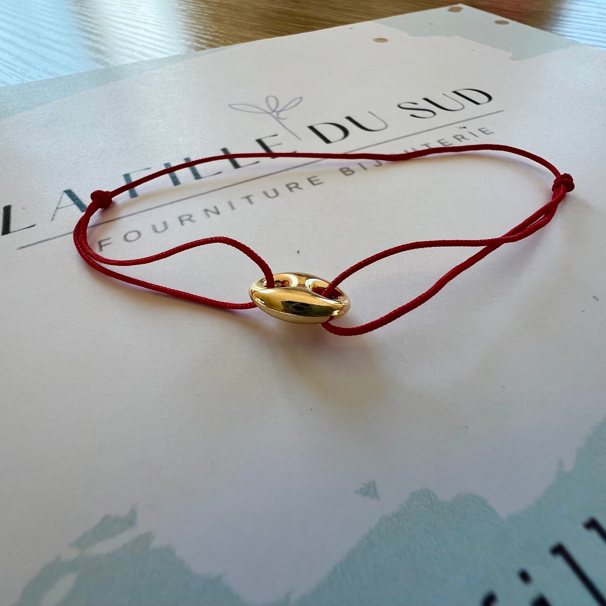 Bracelet cordon rouge porte-bonheur avec un graine de café en or 18 carats.