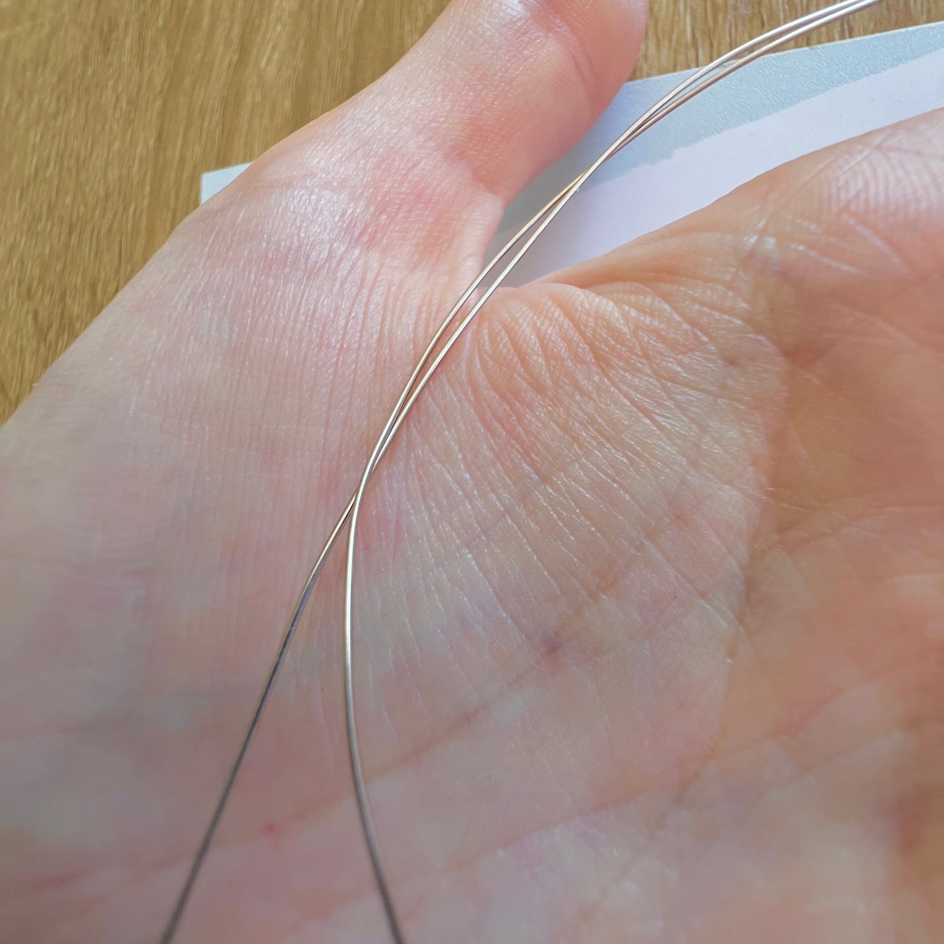 Détail de deux fils d'or ronds de 0,50mm en or gris palladié, idéal pour fabriquer des maillons ou apprêts fins.