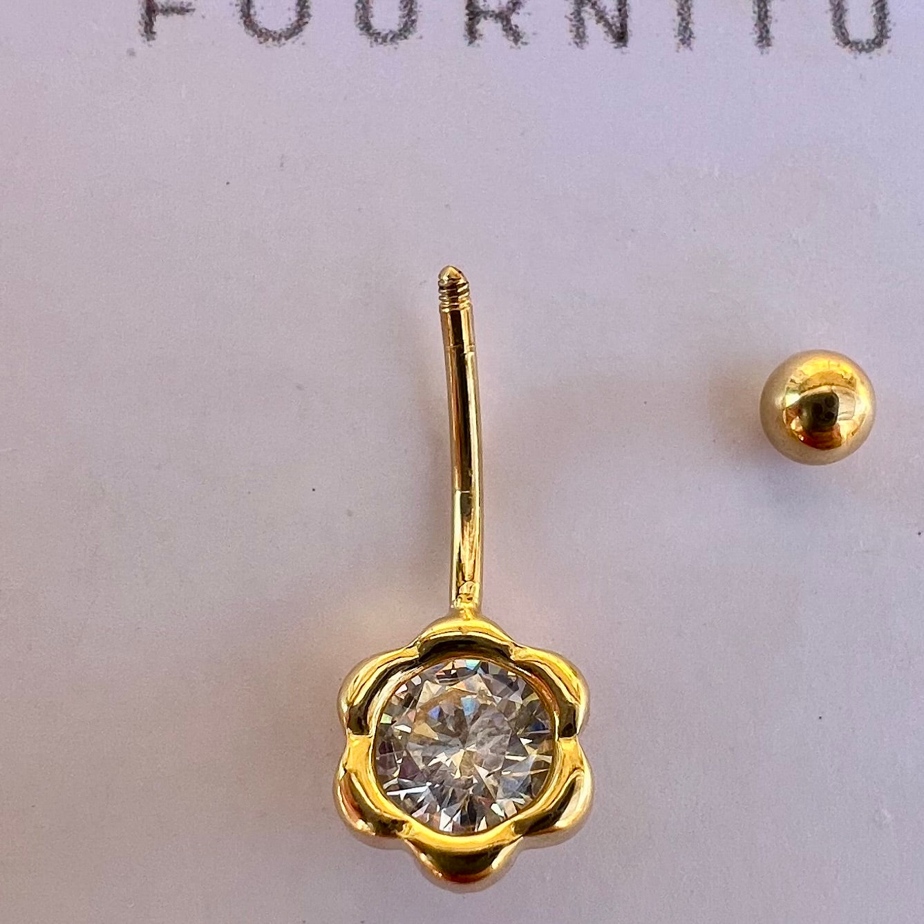Détail du système de fermeture à vis avec la boule supérieure dévissable en or jaune 18 carats du piercing de nombril.