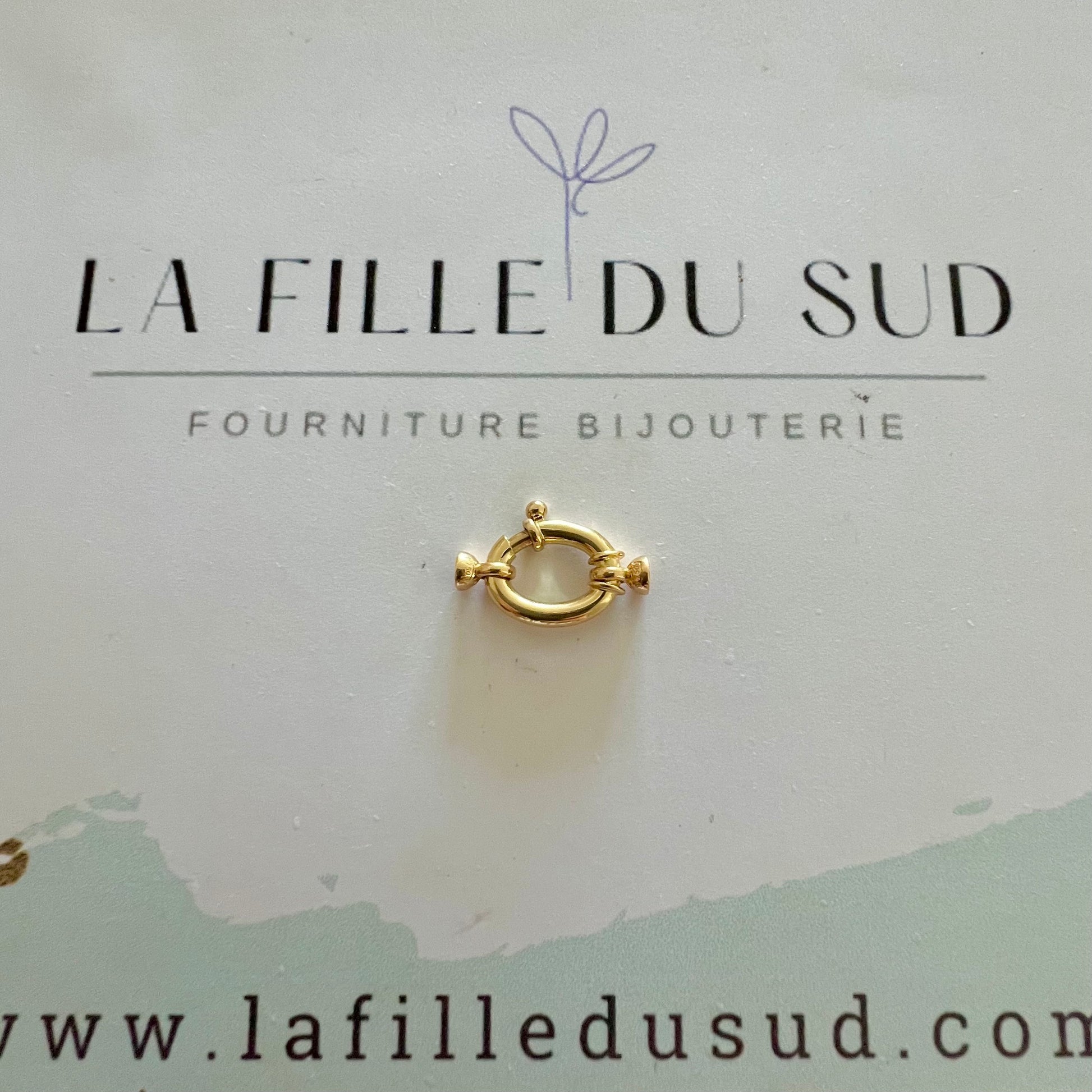 Fermoir bouée ovale en or 18 carats présenté sur la carte de l'atelier de fournitures de bijouterie.
