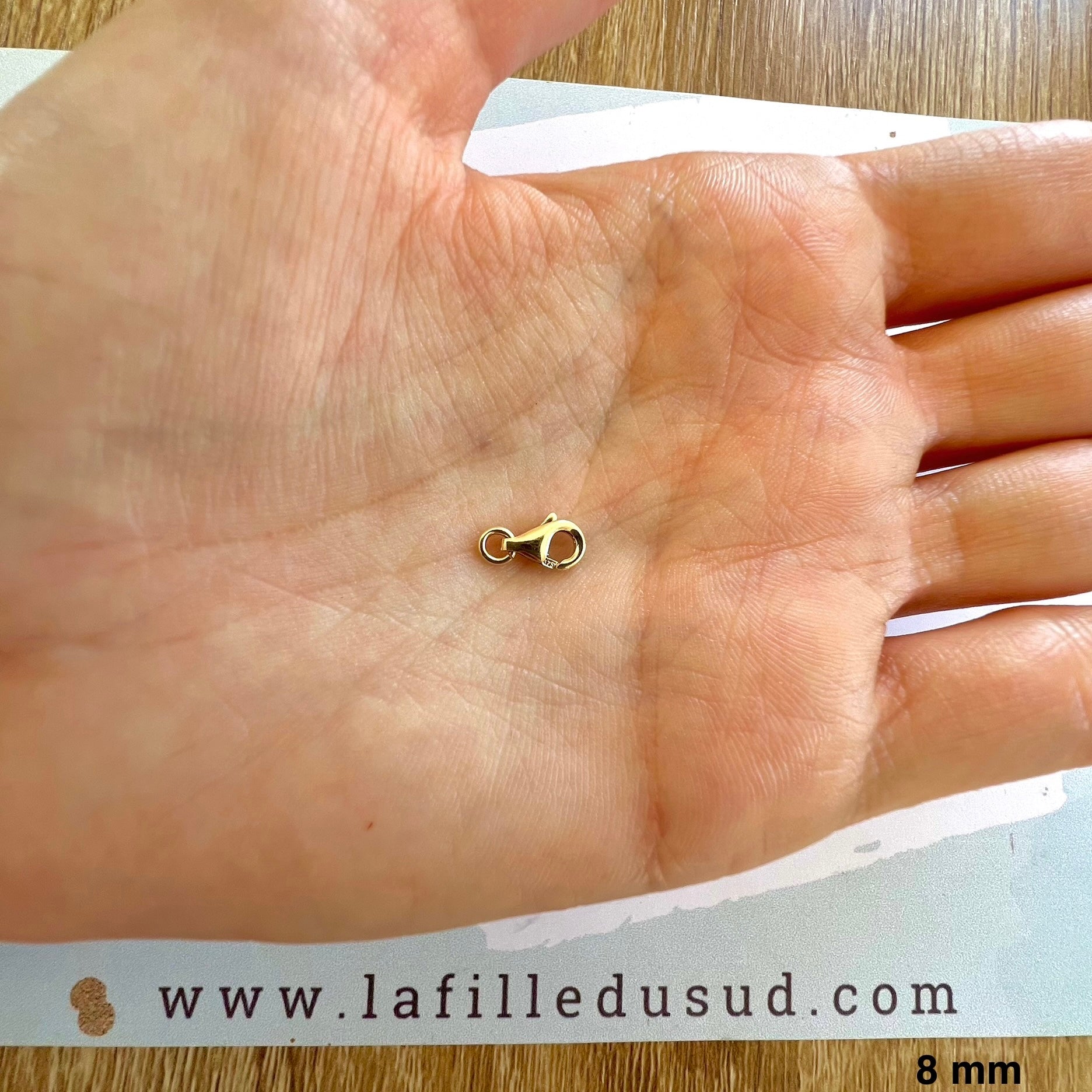 Fermoir mousqueton de 8 mm en or jaune 9 carats dans la main.