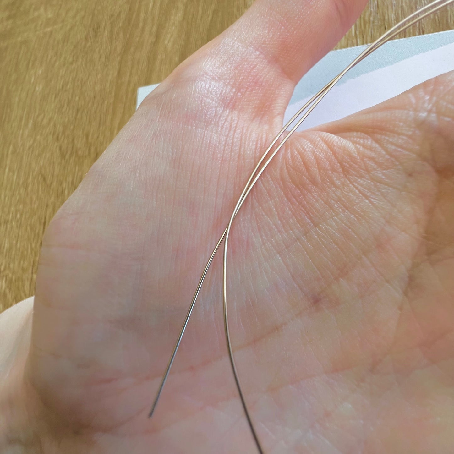 Texture lisse et brillante du fil d'or blanc non rhodié 18k au creux de la main d'un créateur.