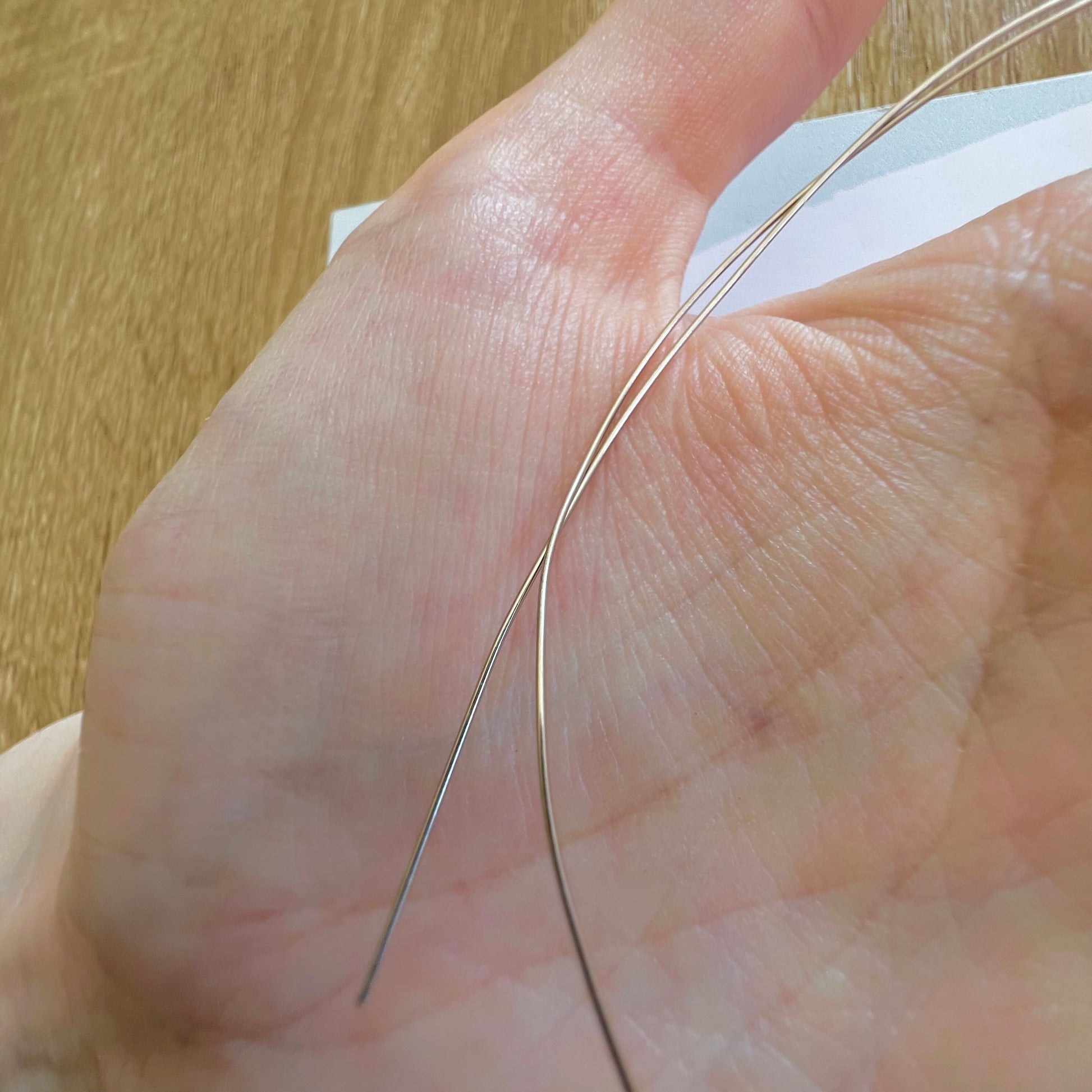 Texture lisse et brillante du fil d'or blanc non rhodié 18k au creux de la main d'un créateur.