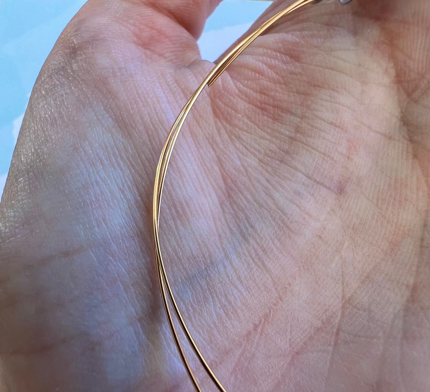 Aperçu de la finesse et de la souplesse d'un fil d'or rose 18k de 0,50 mm dans la main