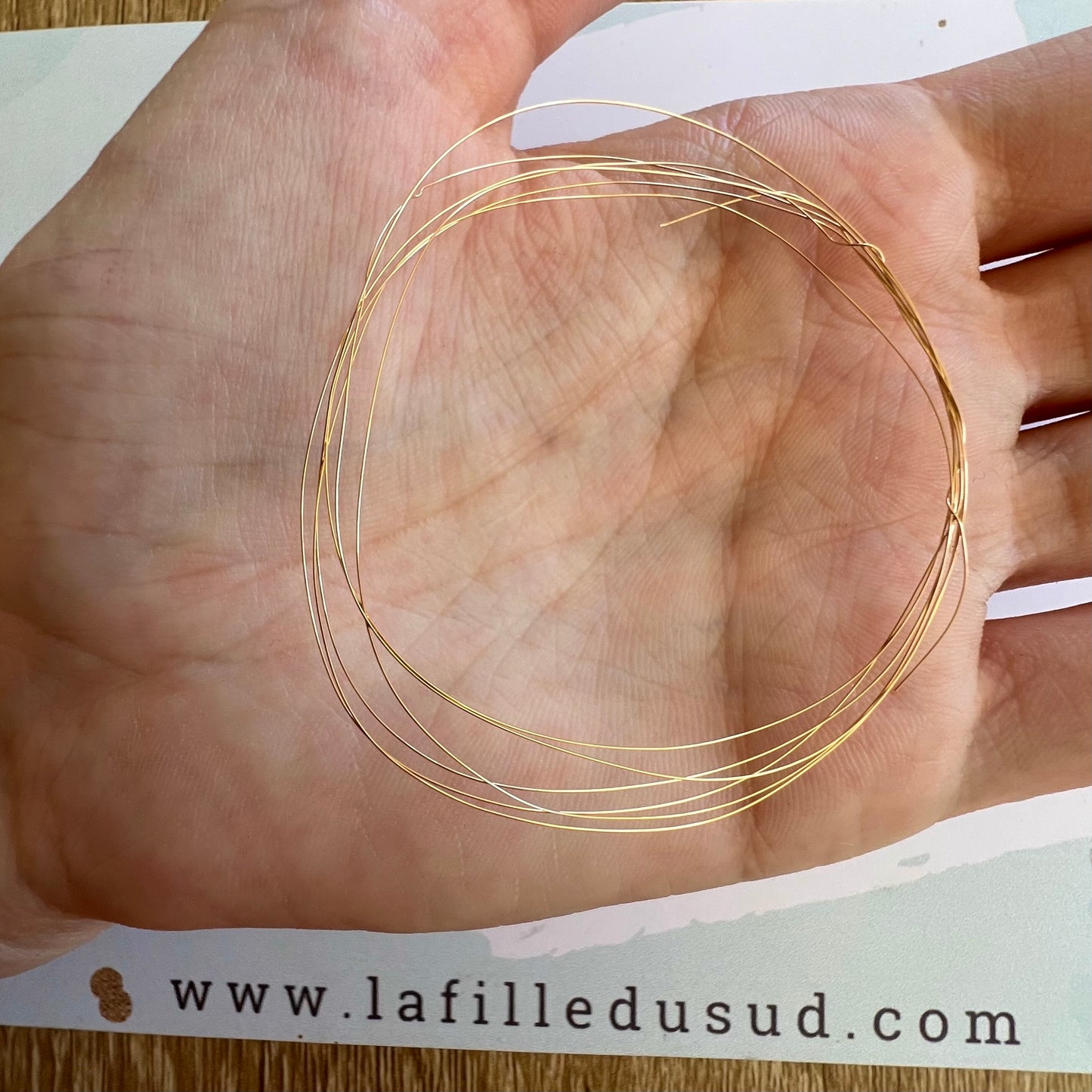 Gros plan sur la finesse extrême d'un fil d'or rose 18 carats de 0,20 mm dans la main.