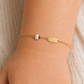 Bracelet identité pour bébé avec coccinelle blanche en or jaune 18 carats, porté au poignet pour un style pur et élégant.