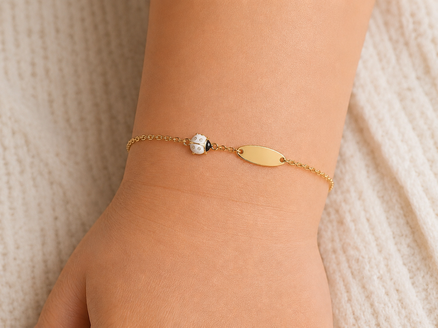 Bracelet identité pour bébé avec coccinelle blanche en or jaune 18 carats, porté au poignet pour un style pur et élégant.