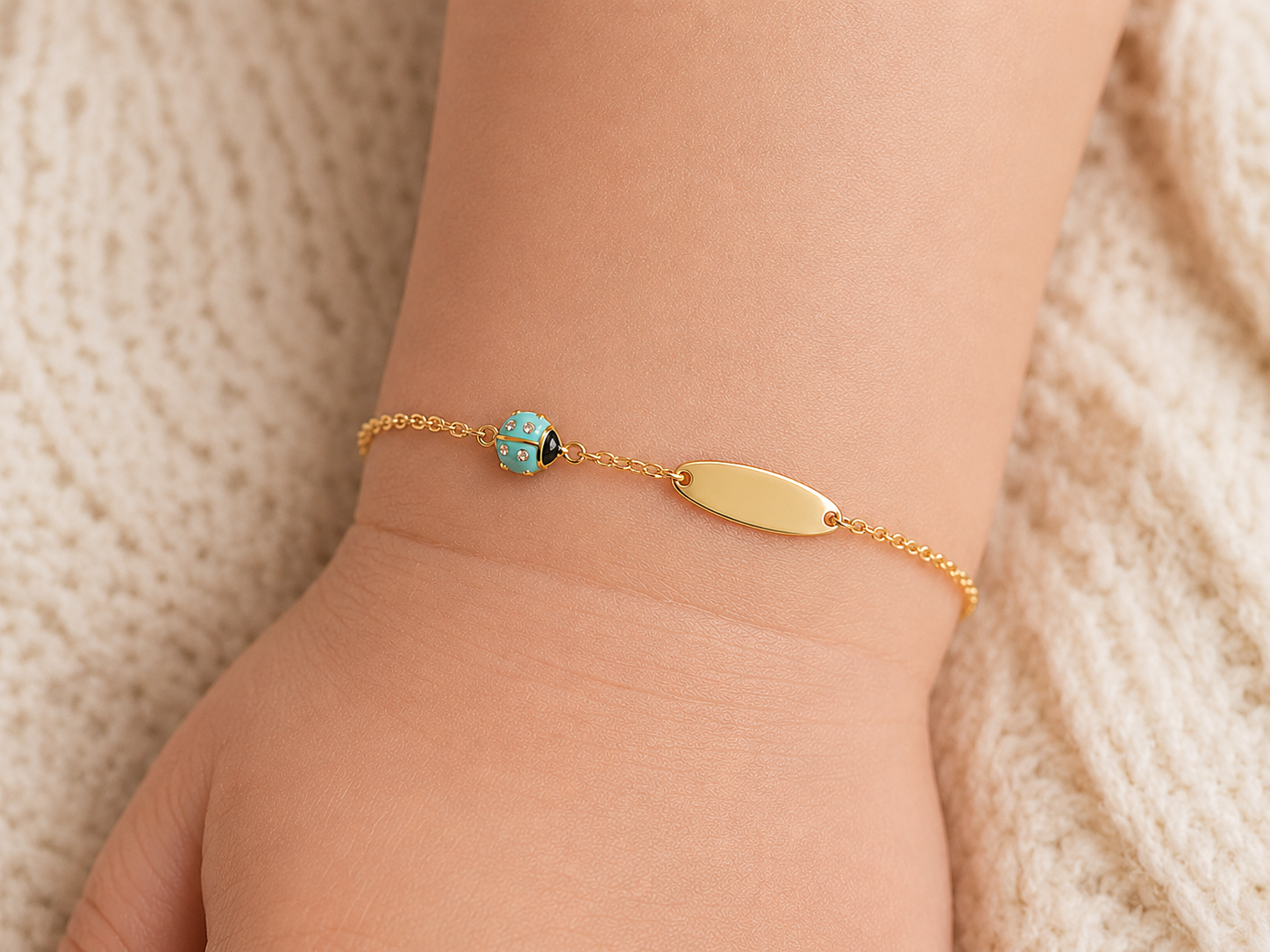 Rendu d'une gourmette bébé coccinelle bleue turquoise en or 18 carats sur la peau, un bijou de naissance original et coloré.