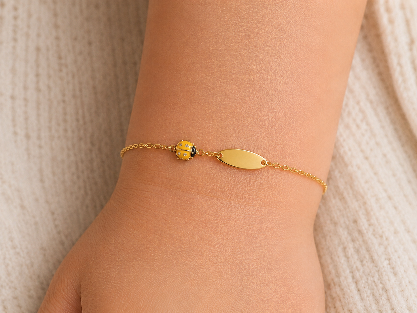Gourmette bébé coccinelle jaune solaire en or 18 carats massif, vue du bijou ajustable porté par un enfant.