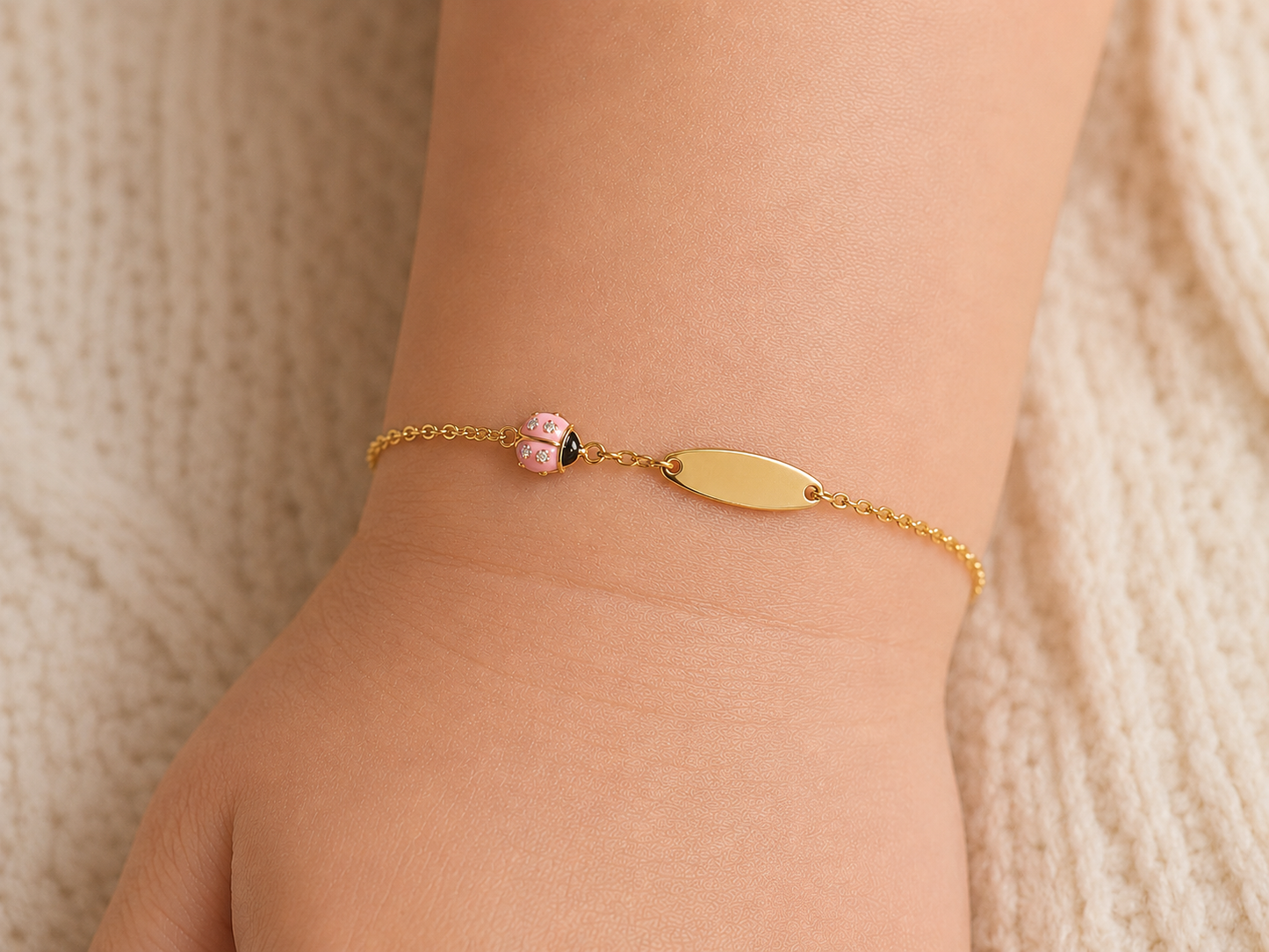 Gourmette pour bébé fille avec motif coccinelle rose en résine et or jaune 18 carats, vue du bijou porté.