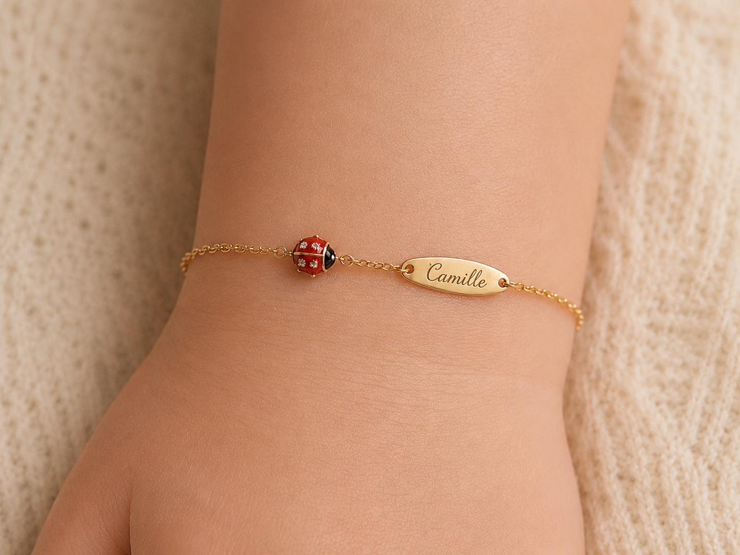 Exemple de personnalisation avec gravure de prénom sur la plaque d'une gourmette bébé coccinelle en or 18 carats.
