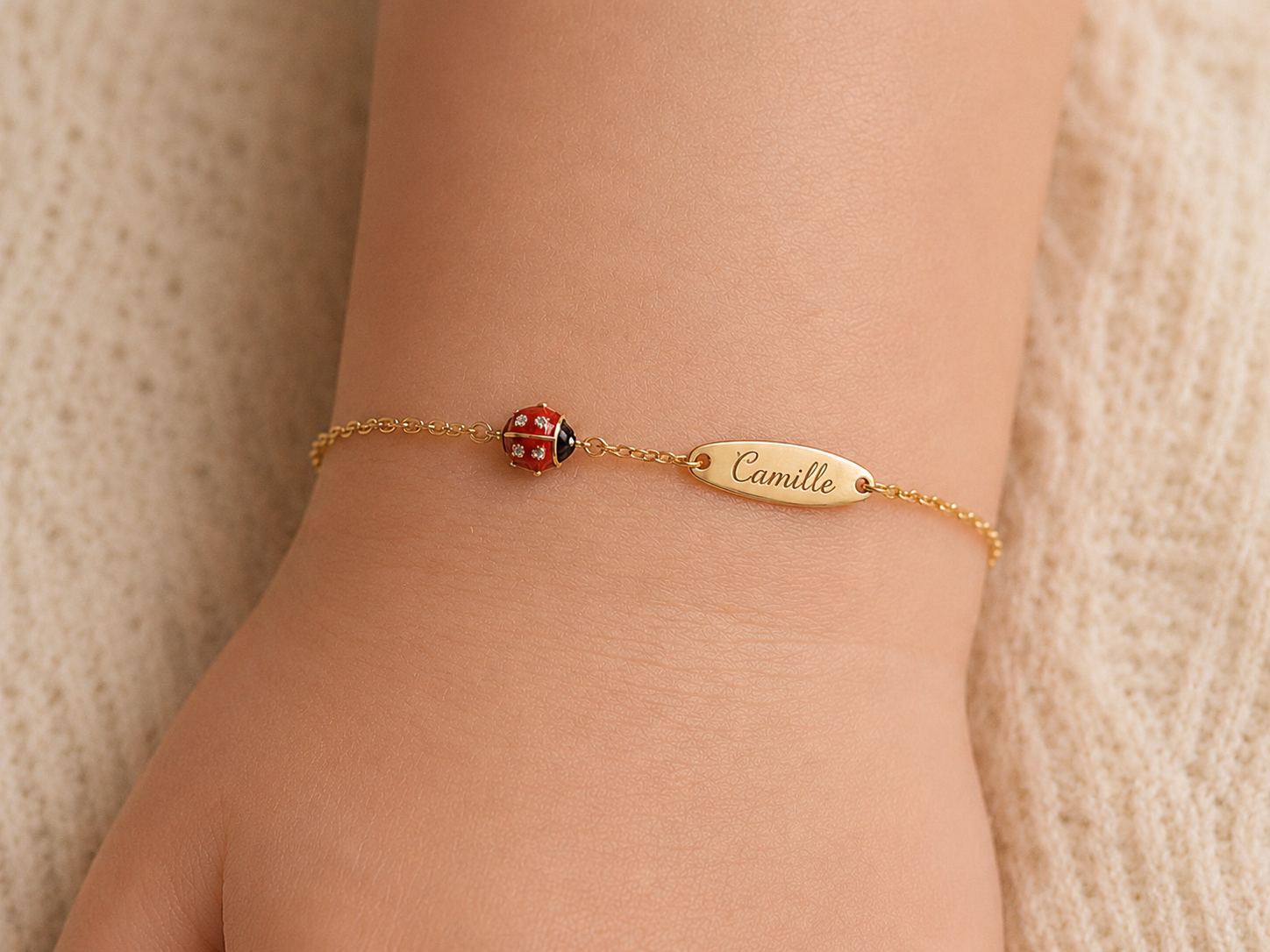 Exemple de personnalisation avec gravure de prénom sur la plaque d'une gourmette bébé coccinelle en or 18 carats.
