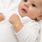Bébé portant une gourmette de naissance en or jaune 18 carats avec plaque à graver.