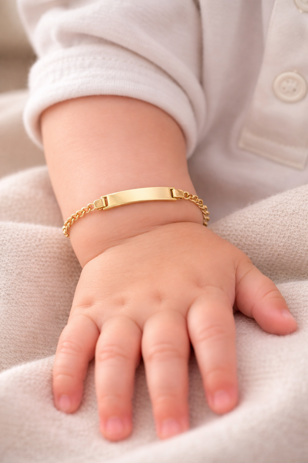 Bébé portant une gourmette de naissance en or jaune 18 carats avec plaque à graver.
