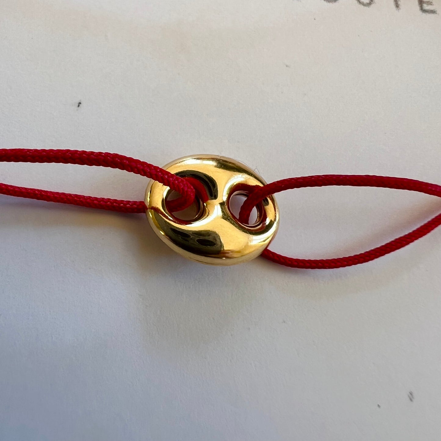Bracelet cordon rouge porte-bonheur avec un graine de café en or 18 carats.
