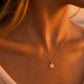 Gros plan sur le décolleté d'une femme portant la petite médaille de l'Ange à la Colombe en or jaune 18 carats, diamètre 14 mm, style bijou de peau.