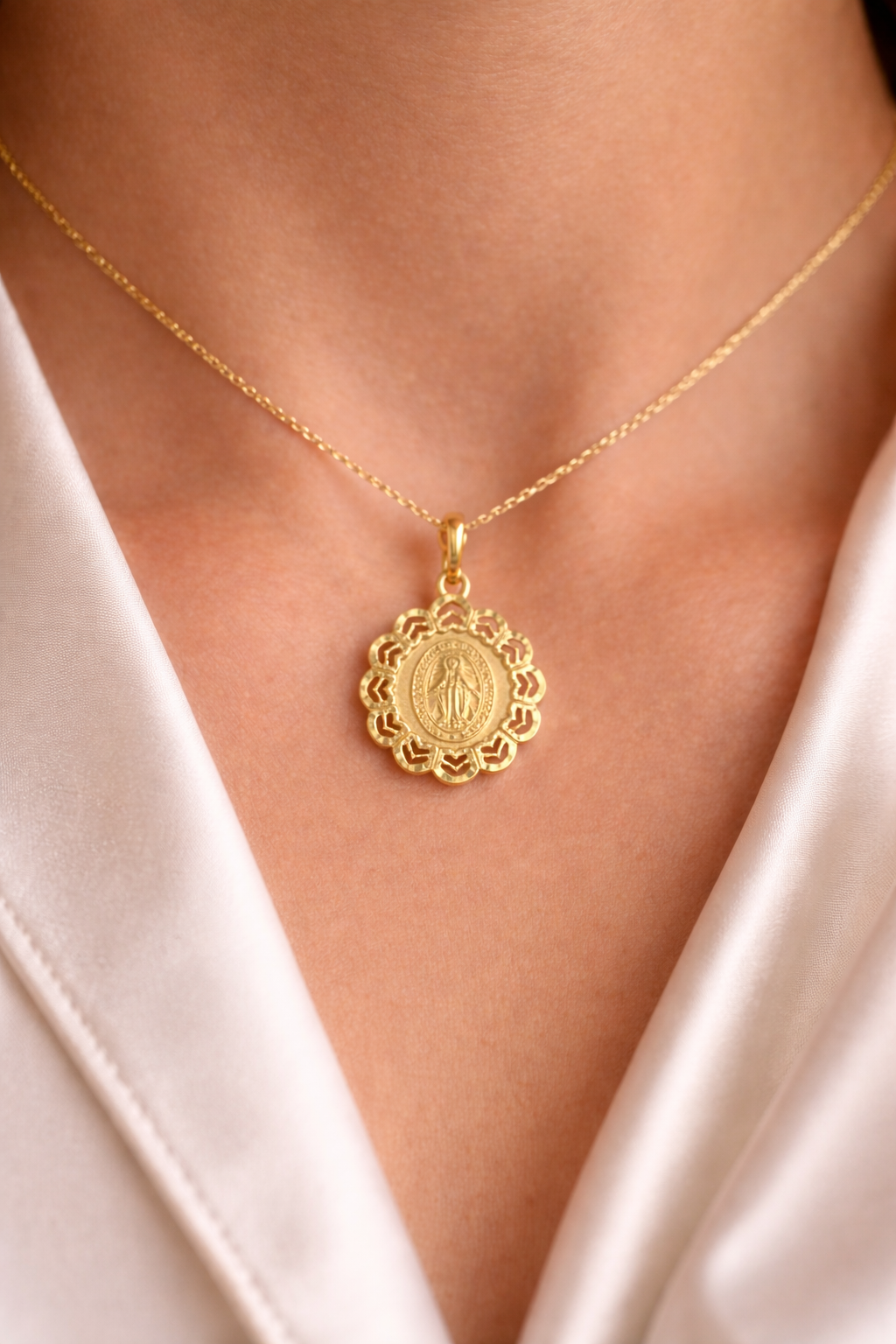 Médaille miraculeuse en or jaune 18 carats avec entourage ajouré, portée au cou par une femme.