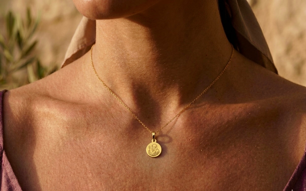 Gros plan sur une femme portant la médaille de Saint Benoît en or jaune 18 carats, un puissant symbole de protection de 16 mm de diamètre.