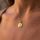 Gros plan sur une femme portant la médaille de Saint Michel Archange en or jaune 18 carats, un pendentif de protection de 16 mm de diamètre.