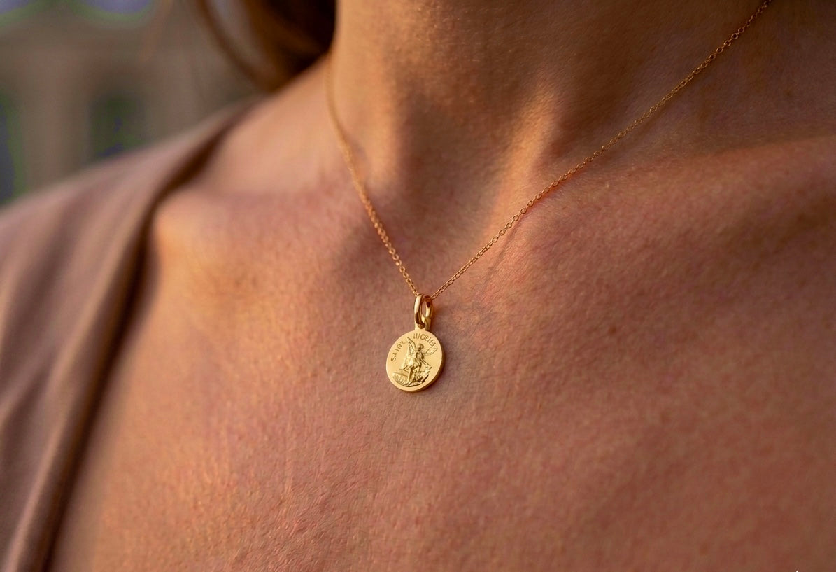 Gros plan sur une femme portant la médaille de Saint Michel Archange en or jaune 18 carats, un pendentif de protection de 16 mm de diamètre.