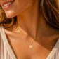 Gros plan sur une femme portant le pendentif ange en or 18 carats et nacre naturelle, une médaille de 14 mm au style doux et solaire.