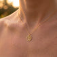 Gros plan sur une femme portant le pendentif Arbre de Vie en or jaune 18 carats, modèle ajouré de 18 mm avec détails de branches et racines.