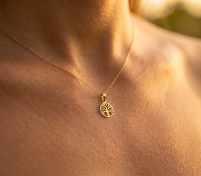 Gros plan sur le décolleté d'une femme portant le petit pendentif Arbre de Vie en or jaune 18 carats, médaille ajourée de 13 mm au style solaire.