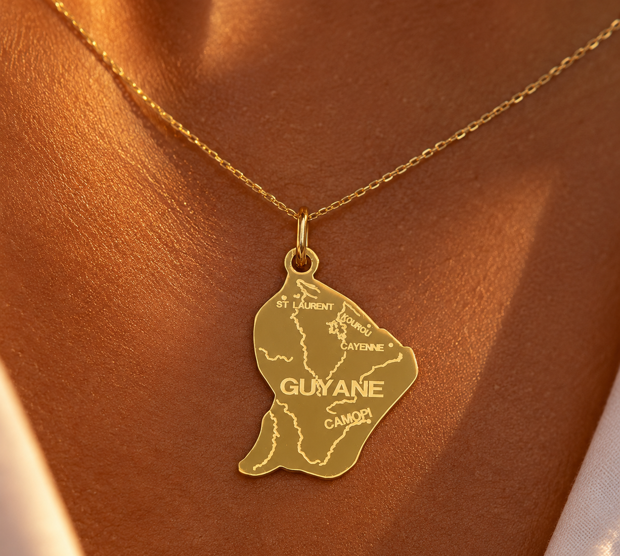 Pendentif carte de la Guyane en or 18 carats massif porté sur un décolleté féminin avec une chaîne en or jaune.