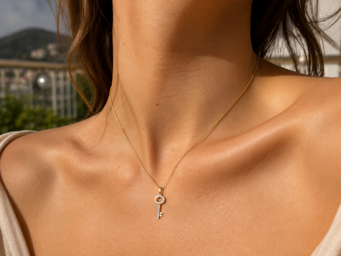 Gros plan sur le décolleté d'une femme portant un pendentif en forme de clé en or jaune 18 carats serti de diamants naturels.