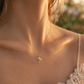 Gros plan sur le décolleté d'une femme portant le pendentif colibri en or jaune 18 carats, un bijou d'oiseau en relief délicat et brillant.