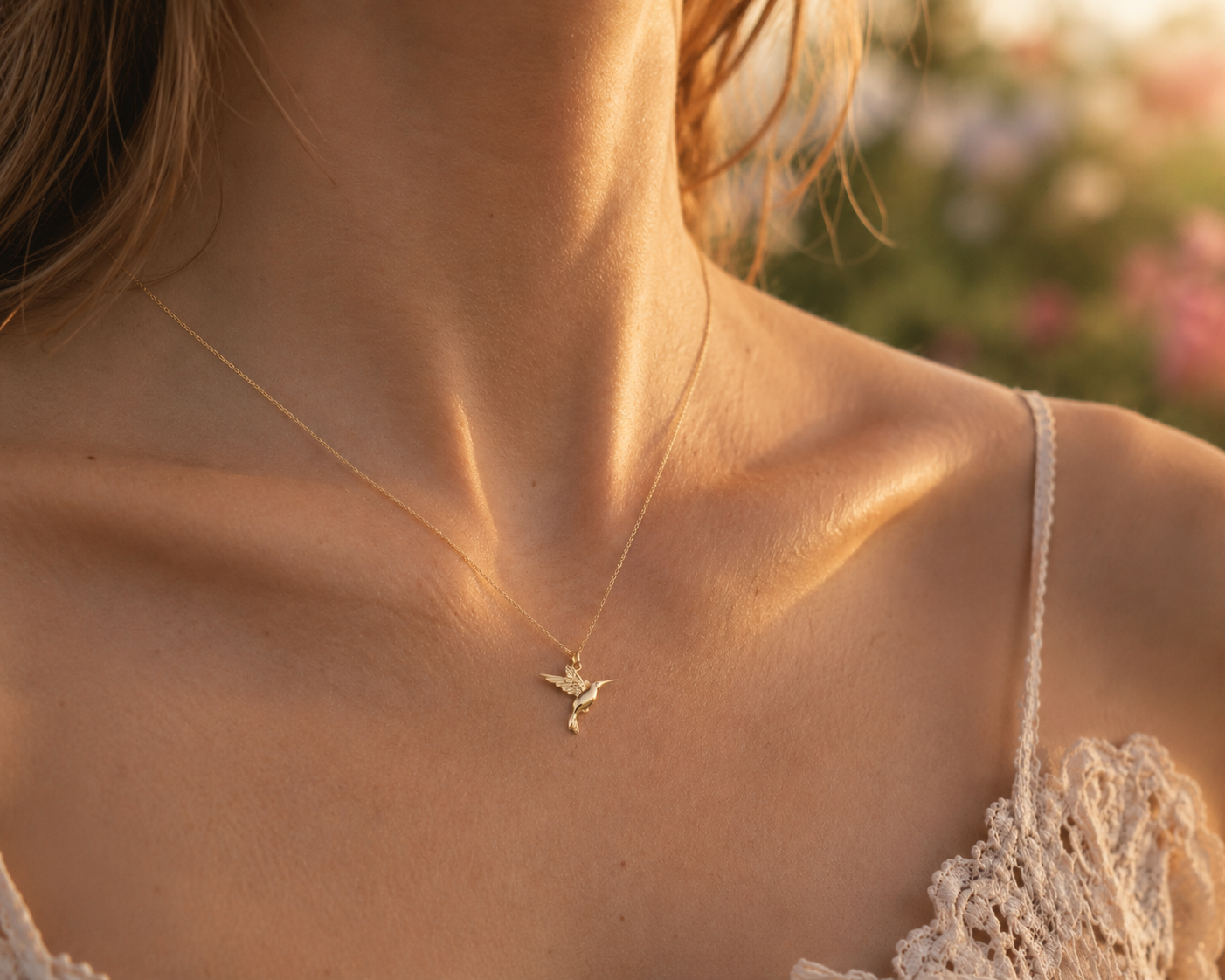 Gros plan sur le décolleté d'une femme portant le pendentif colibri en or jaune 18 carats, un bijou d'oiseau en relief délicat et brillant.