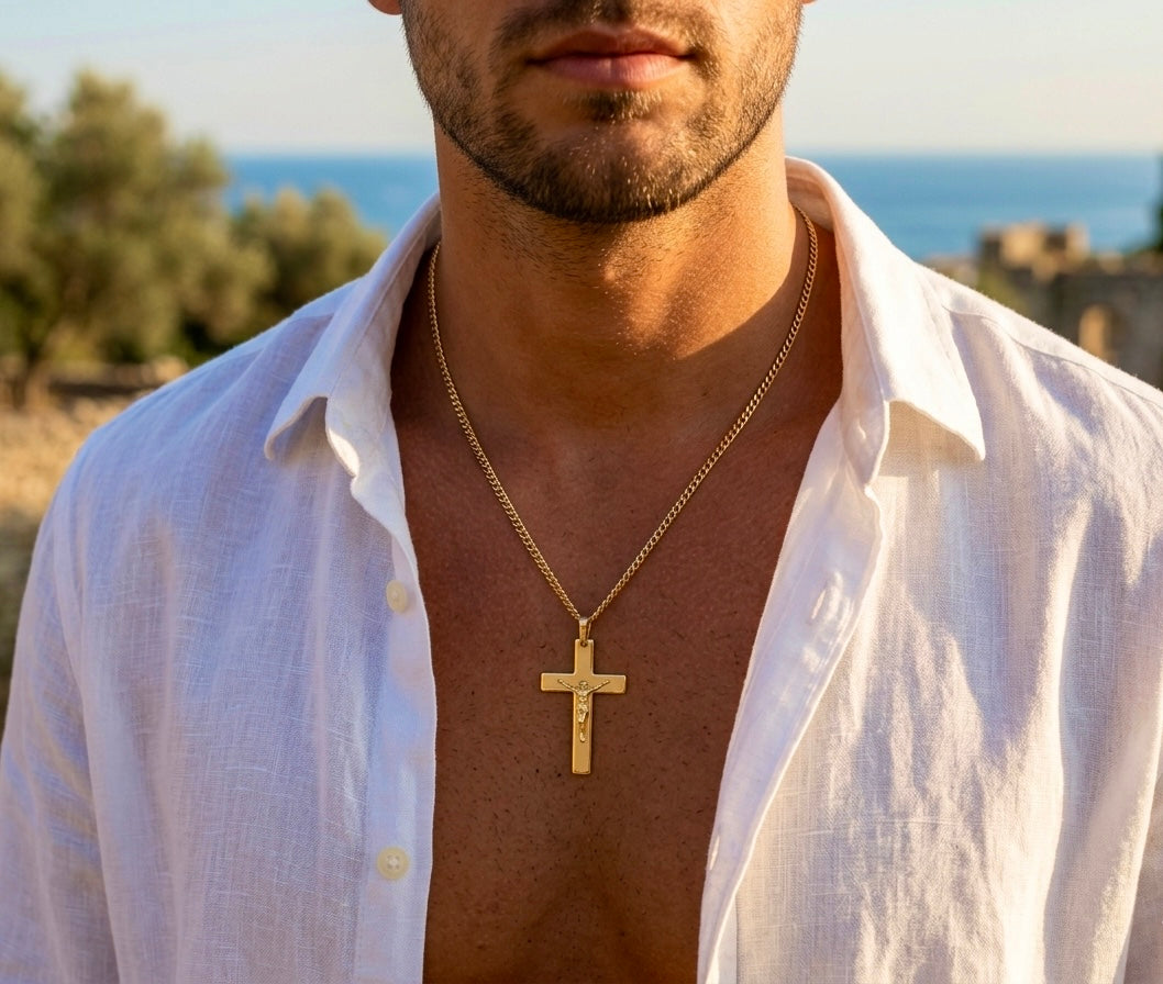 Gros plan sur le torse d'un homme portant un pendentif de croix avec le Christ en or jaune 18 carats, un bijou religieux de luxe au fini poli et satiné.