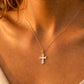 Gros plan sur une femme portant le pendentif croix en or 18 carats et nacre véritable, une médaille de 22 mm aux reflets irisés.