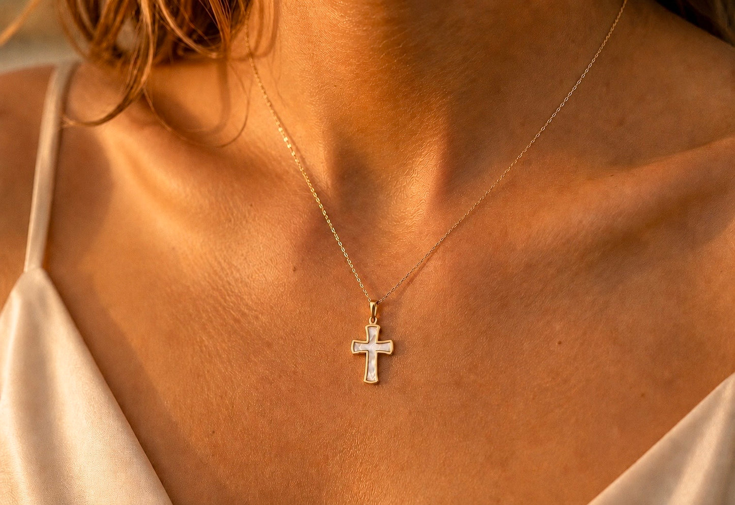 Gros plan sur une femme portant le pendentif croix en or 18 carats et nacre véritable, une médaille de 22 mm aux reflets irisés.