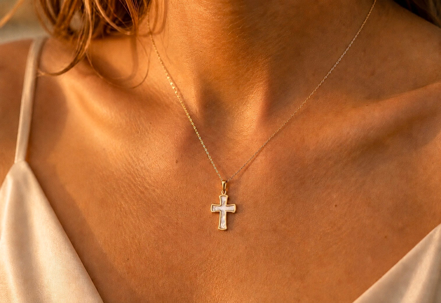 Gros plan sur une femme portant le pendentif croix en or 18 carats et nacre véritable, une médaille de 22 mm aux reflets irisés.