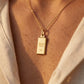 Pendentif lingot d'or 18 carats massif de 1 gramme porté sur une chaîne en or au coucher du soleil.