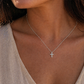 Femme portant la petite croix diamant en or blanc 18k au soleil couchant.